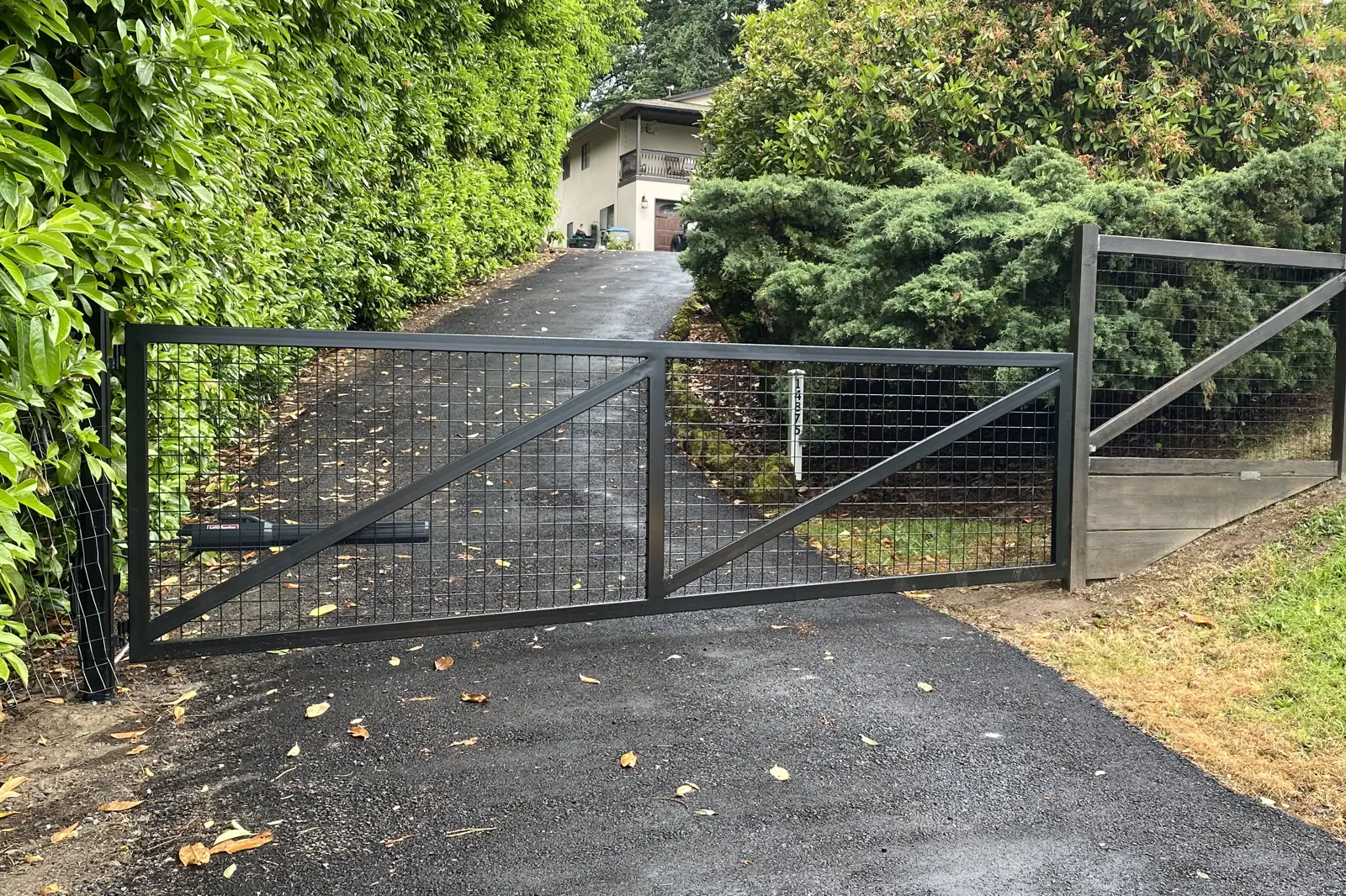 Black metal automatic swing gate with wire mesh infill