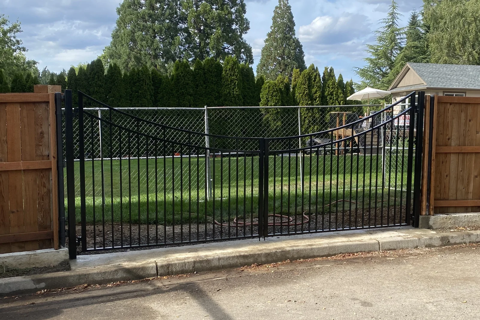 Black metal driveway gate with scalloped top edge