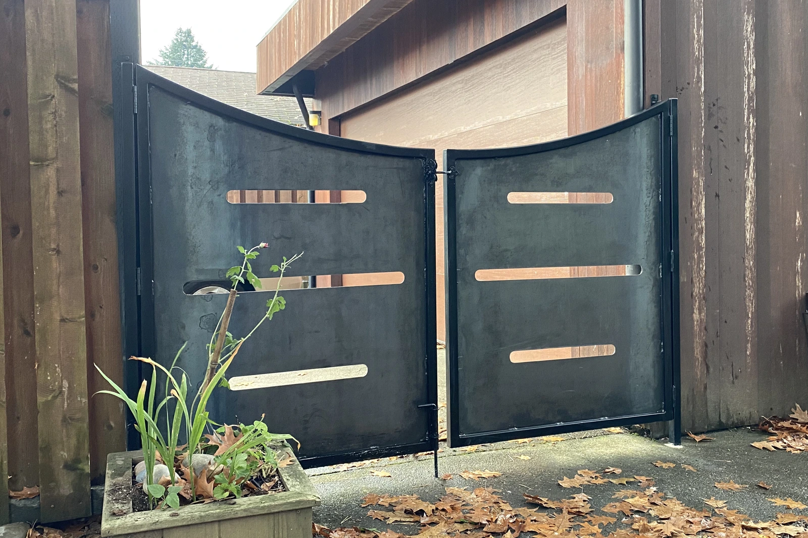 Modern black metal privacy gate with horizontal slat cutouts