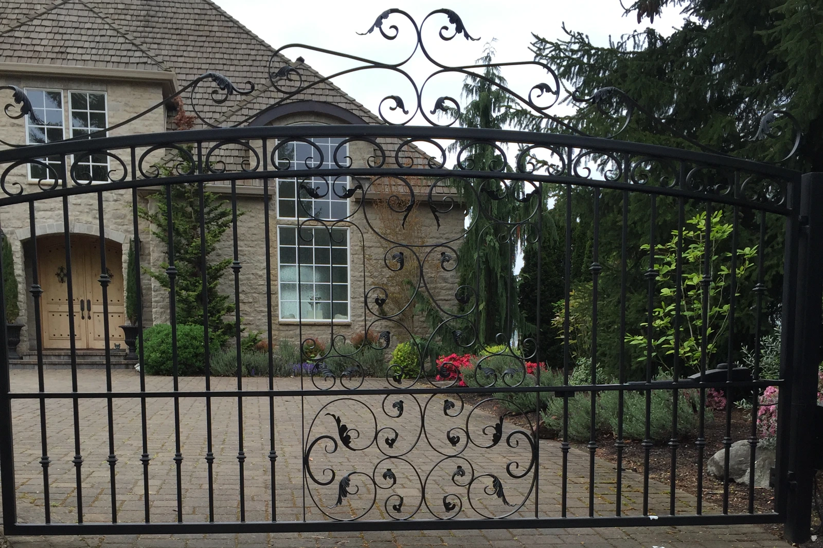 Black ornate wrought iron driveway gate with arched top | Chip and Dale's Iron Works