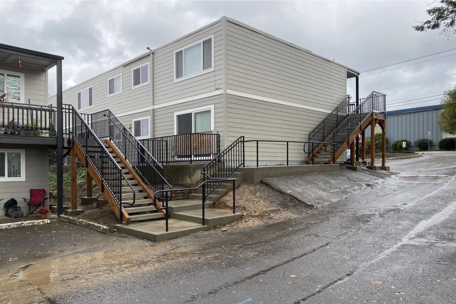 Custom-fabricated black metal commercial stairwell railing with vertical pickets, installed on exterior apartment building stairs with integrated ADA-compliant handrails.