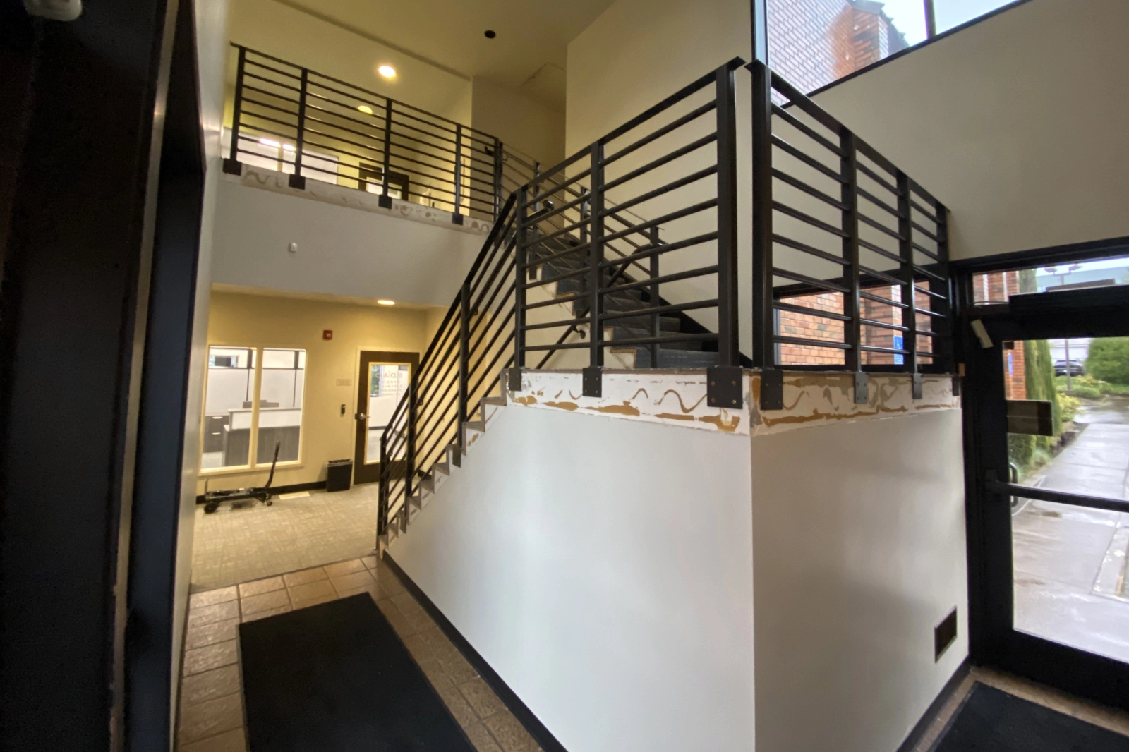 Custom-fabricated commercial interior staircase featuring modern matte black horizontal bar railings and a matching mezzanine guardrail system.