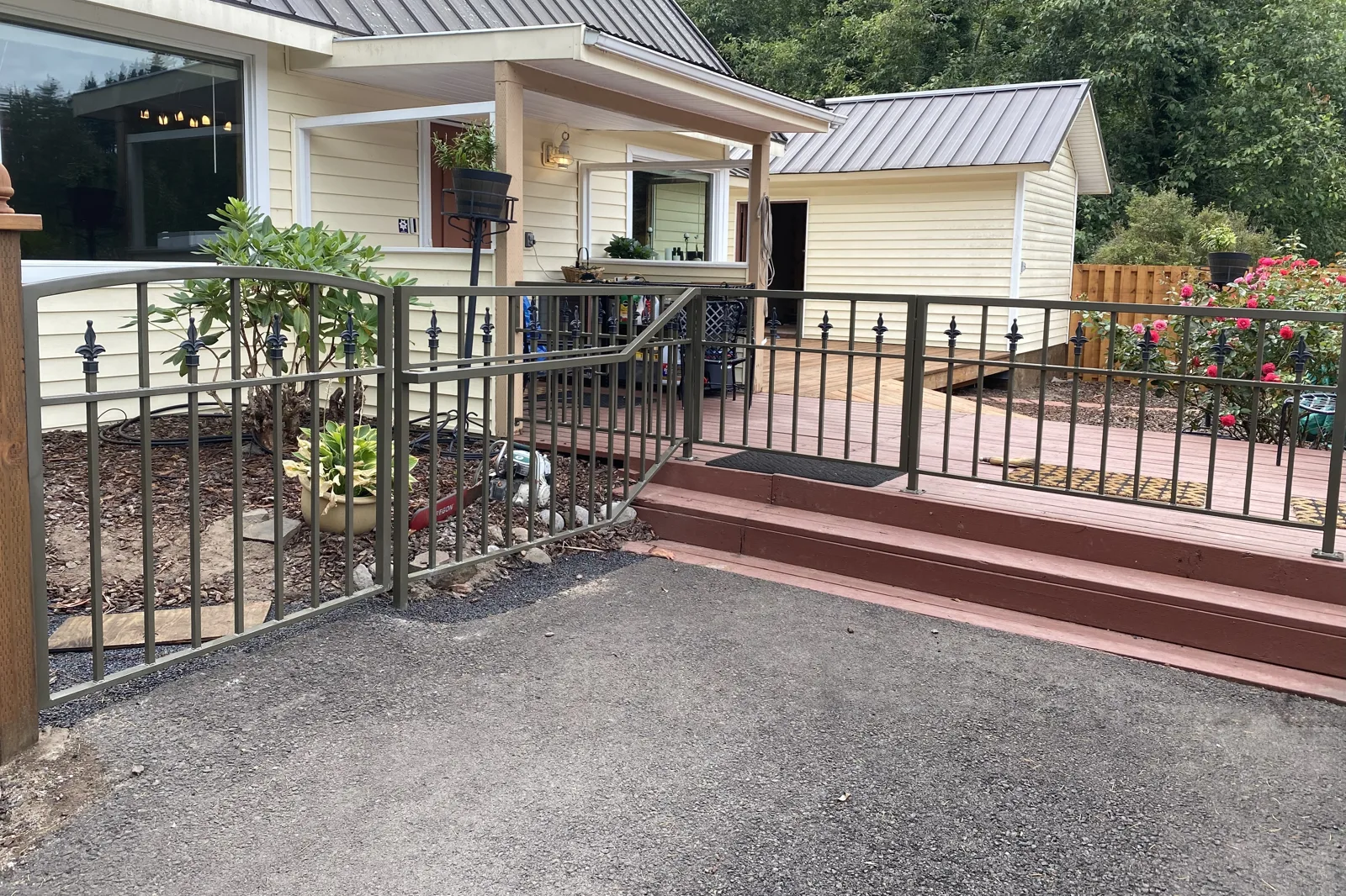 A black residential ornamental iron fence featuring classic spear-top finials, bordering wide wooden entry steps and a matching handrail.