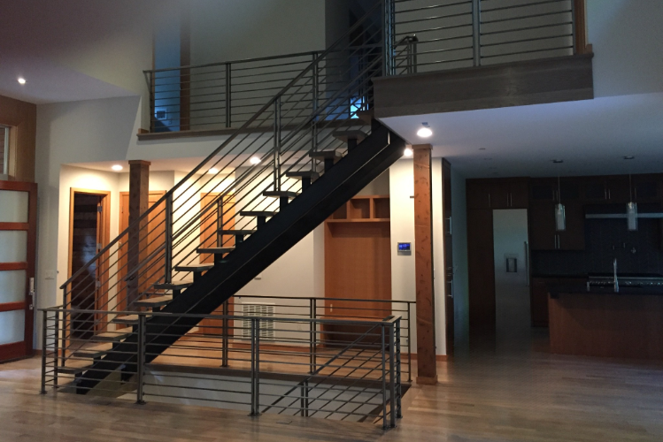 A premium custom-built floating staircase featuring a black steel mono-stringer, open wood treads, and modern horizontal bar railings. | Chip and Dale's Iron Works