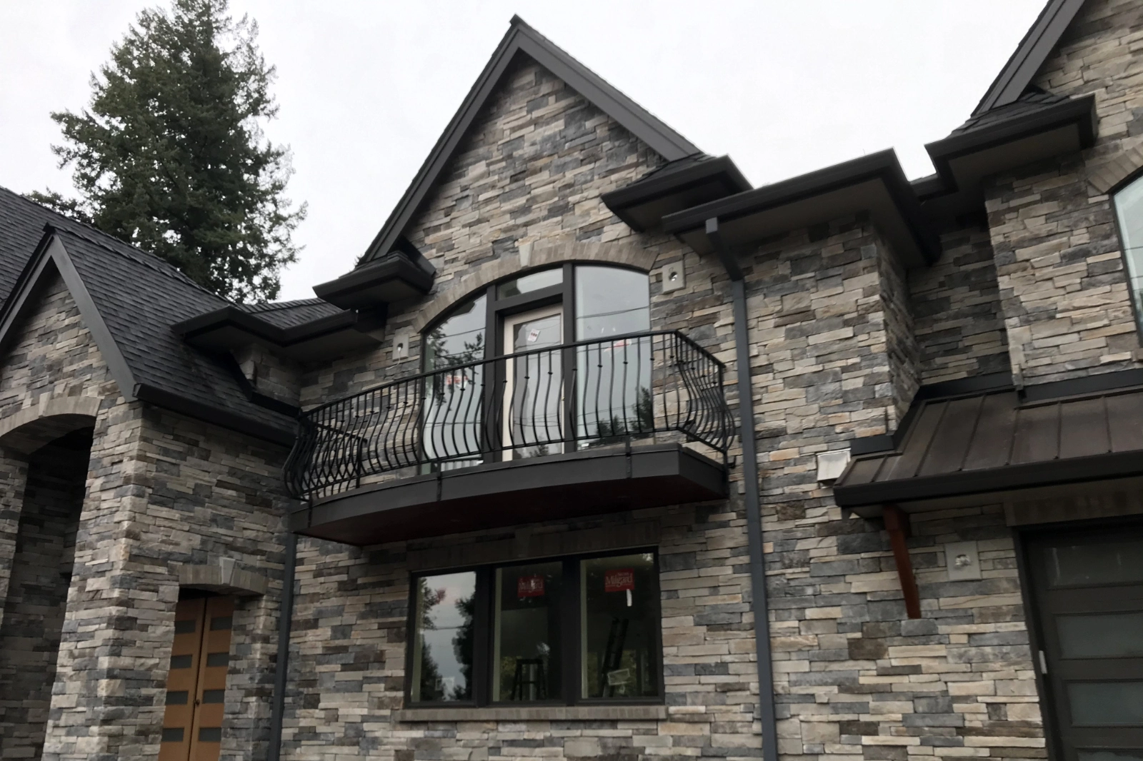A custom-fabricated black wrought iron balcony railing with a decorative bowed-out profile and curved pickets.