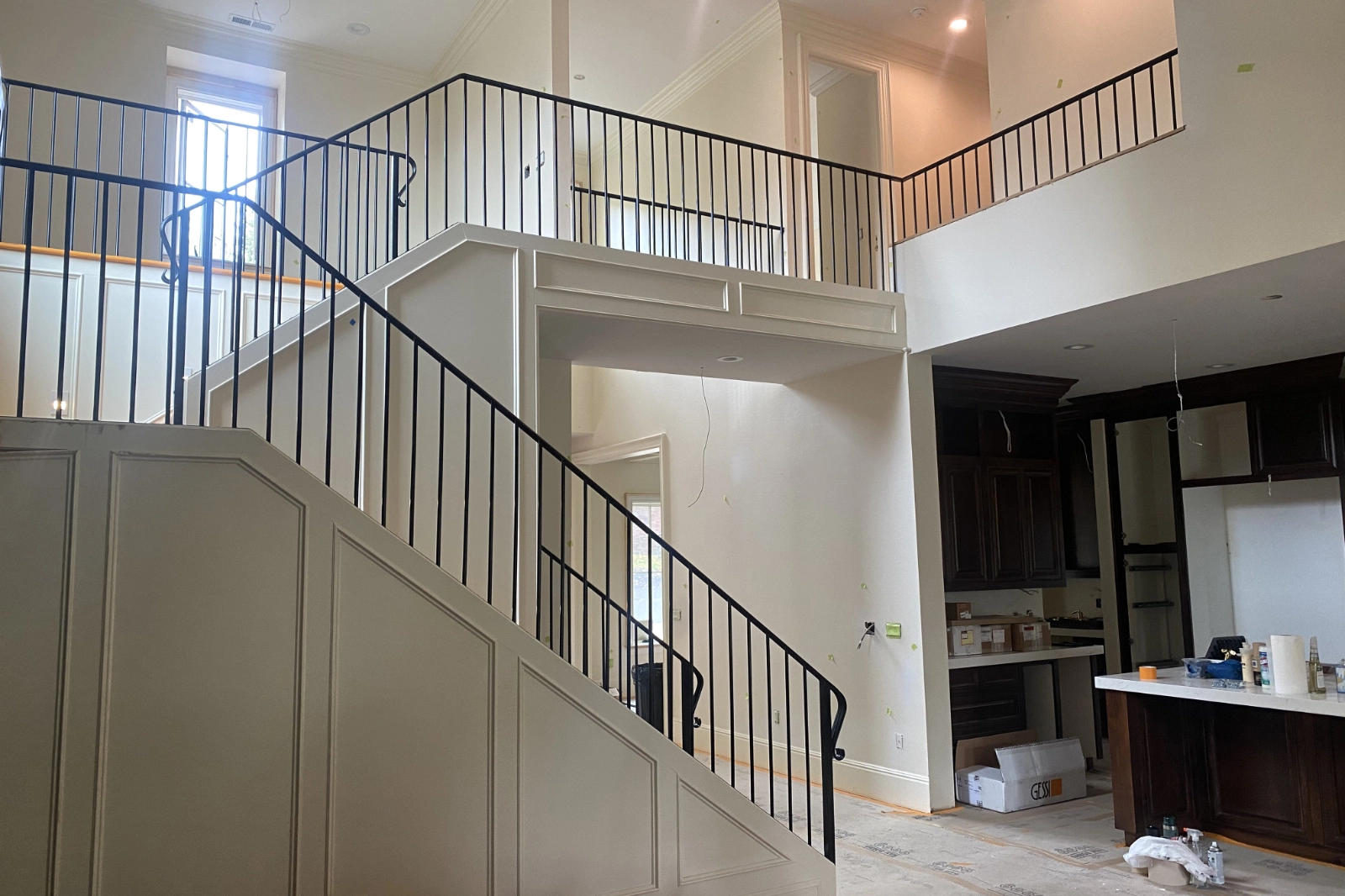 A custom-fabricated black iron staircase railing featuring slim vertical pickets and a matching handrail, installed on a grand staircase.
