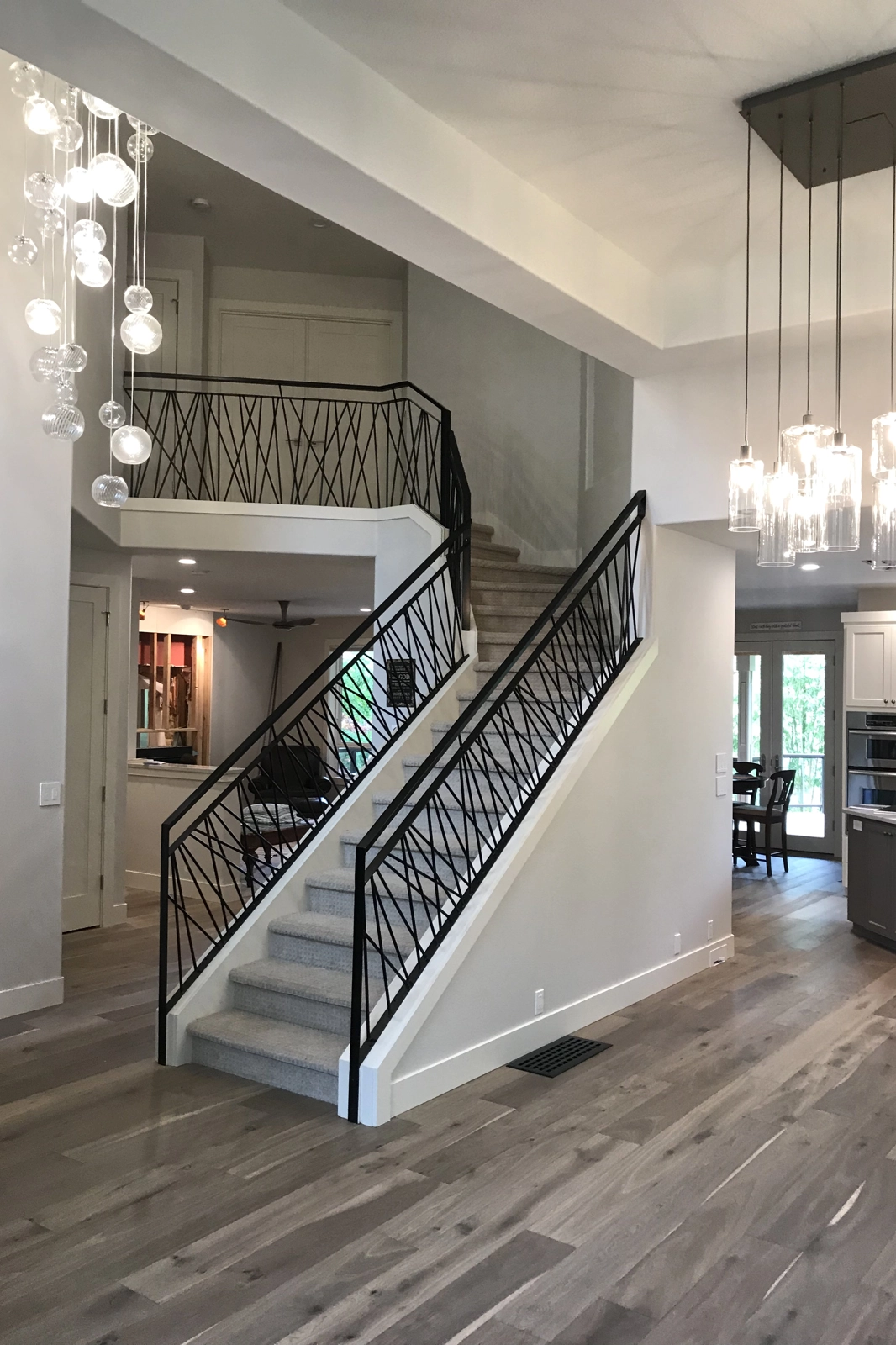 A residential interior railing system featuring black metal with a modern criss-cross geometric picket pattern.