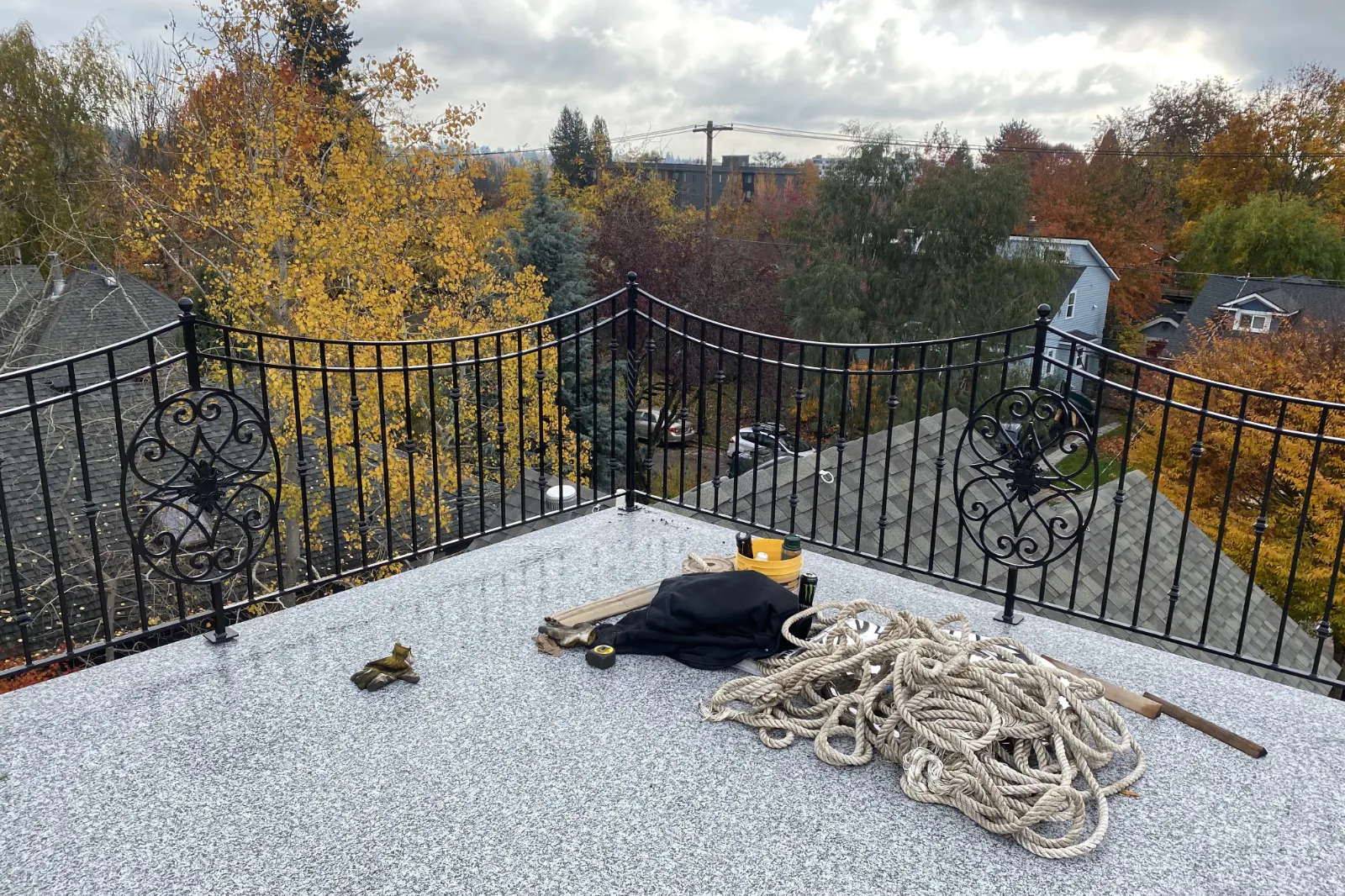 A black wrought iron widow's walk railing featuring decorative circular scrollwork panels and traditional vertical balusters on a rooftop deck.