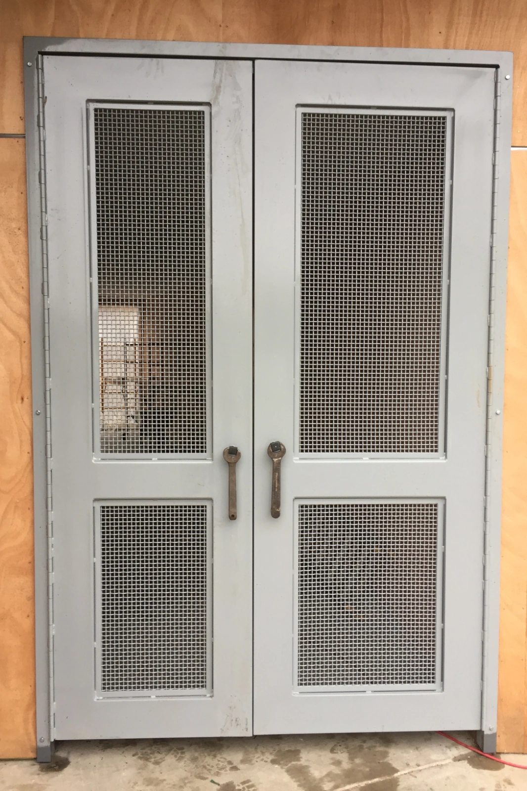 A pair of custom-fabricated gray industrial double doors with integrated square wire mesh screen panels and unique vintage wrench handles. | Chip and Dales Iron Works