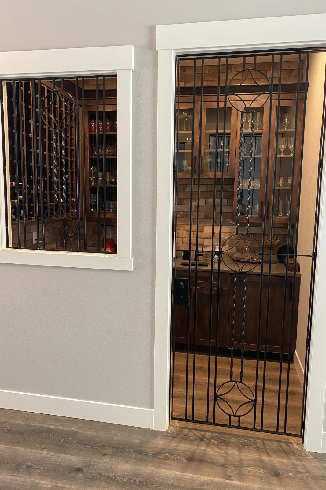 Black wrought iron wine cellar security gate, featuring ornamental circular medallions and twisted metal pickets. | Chip and Dale's Iron Works