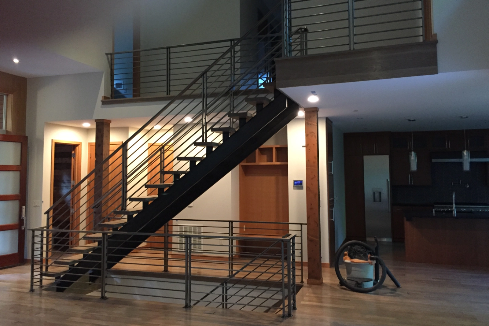 A premium custom-built floating staircase featuring a black steel mono-stringer, open wood treads, and modern horizontal bar railings. | Chip and Dale's Iron Works