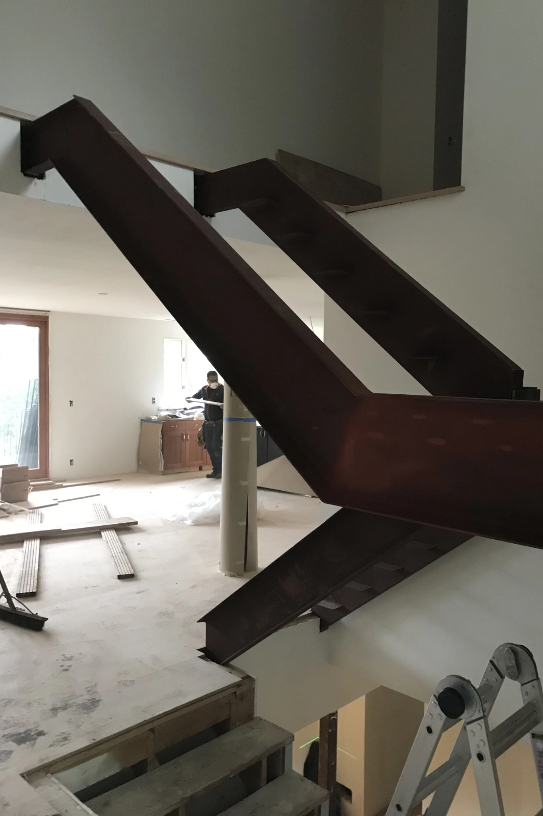 A heavy-duty steel double-stringer staircase frame in a modern residential interior, showcasing precision metal fabrication and engineering.